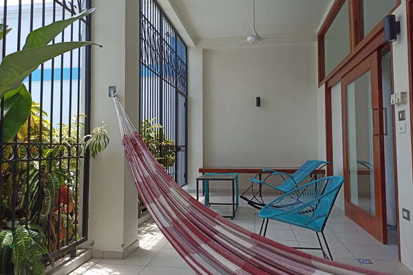 Terraza privada con hamaca y sillas y vista hacia la piscina y a las areas verdes. Ventiladores de techo y luces.