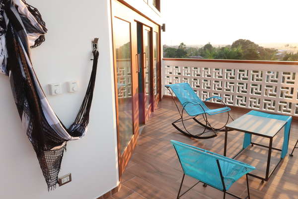 Terraza privada con hamaca y sillas y vista hacia la piscina y a las areas verdes. Ventiladores de techo y luces.