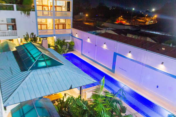 Residencial Morona Flats & Pool de noche, con piscina de 25 m y luces LED de colores, jardines tropicales, sillas largas, maloca, vista hacia la ciudad. Flores, fragancias y grillos. Tranquilidad y privacidad.